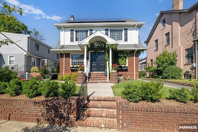 view of front of property featuring roof mounted solar panels and brick siding