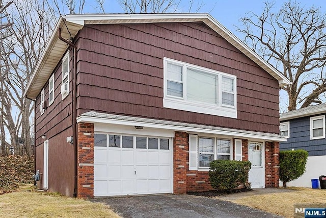 view of front of property with aphalt driveway, an attached garage, and brick siding