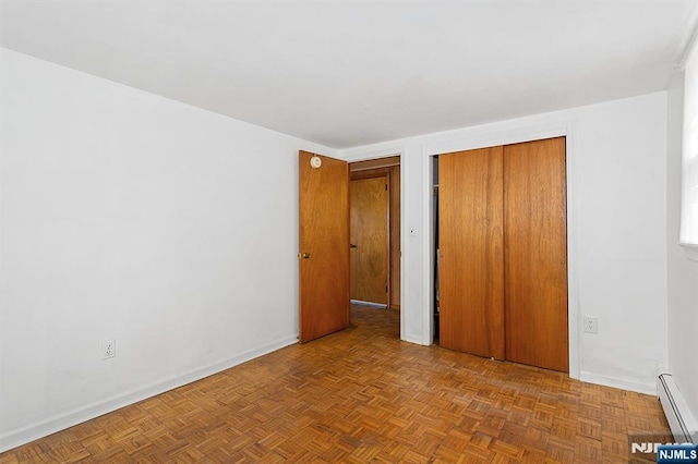 unfurnished bedroom with a closet, baseboards, and a baseboard radiator