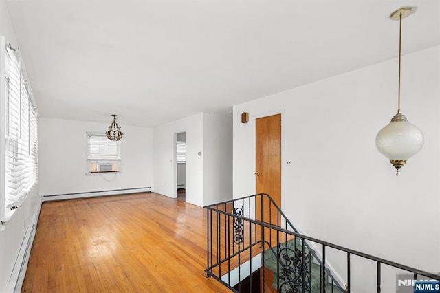 interior space featuring a chandelier, cooling unit, a baseboard heating unit, and light wood-style floors