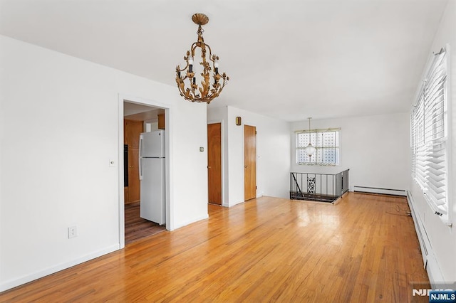 unfurnished living room featuring a chandelier, light wood-style flooring, and a healthy amount of sunlight