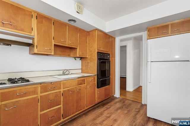 kitchen featuring a warming drawer, under cabinet range hood, a sink, dark wood-style floors, and white appliances