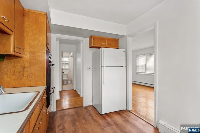 kitchen featuring a sink, a baseboard heating unit, dark wood-type flooring, and freestanding refrigerator