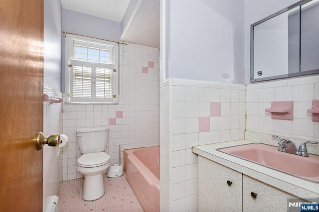 bathroom featuring vanity, tile walls, toilet, a bathtub, and baseboard heating