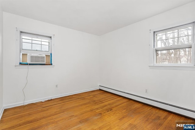 unfurnished room with cooling unit, plenty of natural light, baseboard heating, and light wood-style flooring