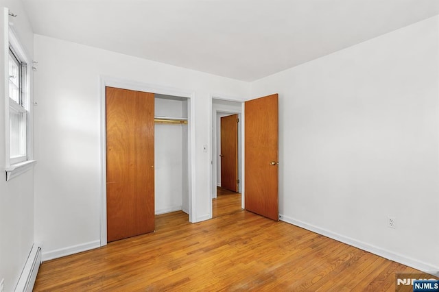 unfurnished bedroom with light wood-style flooring, baseboards, a closet, and baseboard heating