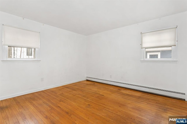 empty room featuring hardwood / wood-style floors, baseboards, and a baseboard radiator