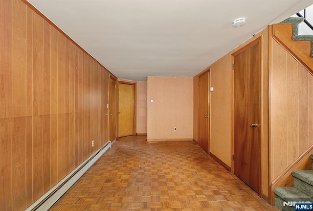 hall with stairway, baseboard heating, and wooden walls