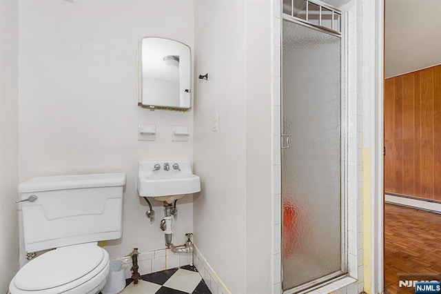 bathroom with a stall shower, a sink, a baseboard heating unit, tile patterned floors, and toilet