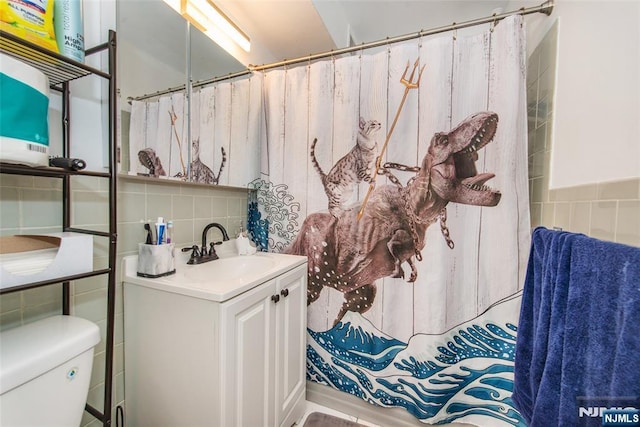 bathroom featuring toilet, tile walls, and vanity