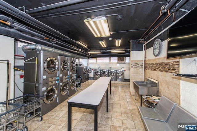 below grade area featuring tile patterned flooring, washing machine and dryer, and stacked washer and clothes dryer