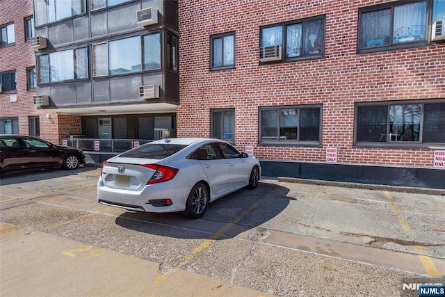 view of property with uncovered parking and a wall mounted air conditioner