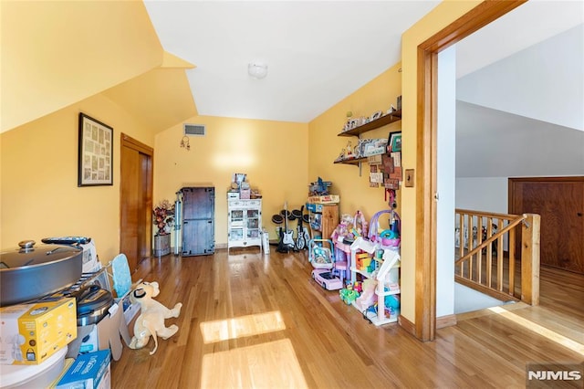 recreation room featuring visible vents, baseboards, wood finished floors, and vaulted ceiling