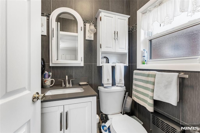 bathroom with vanity, toilet, and radiator