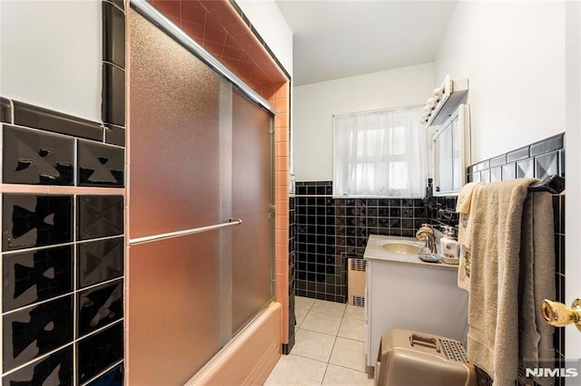 full bathroom featuring vanity, radiator, wainscoting, tile walls, and tile patterned floors