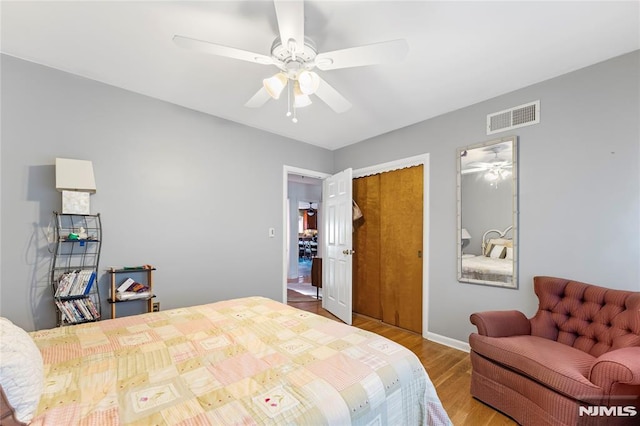 bedroom with wood finished floors, visible vents, a closet, and ceiling fan