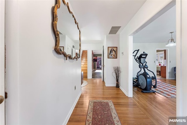 corridor with visible vents, light wood-type flooring, and baseboards