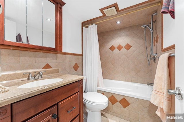 full bathroom with tiled shower / bath, visible vents, toilet, tile walls, and vanity