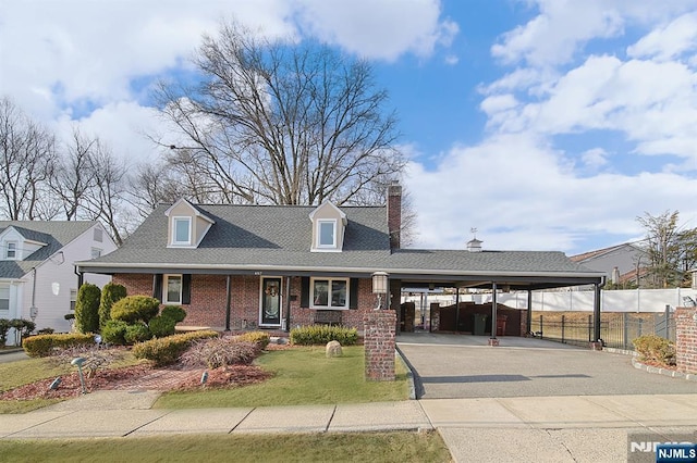 cape cod home featuring a front lawn, aphalt driveway, fence, an attached carport, and brick siding