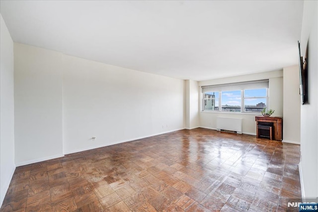 empty room featuring radiator and baseboards