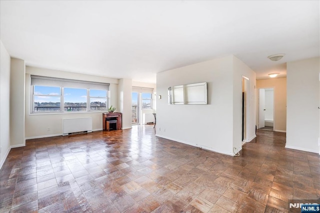 unfurnished living room with baseboards and radiator heating unit