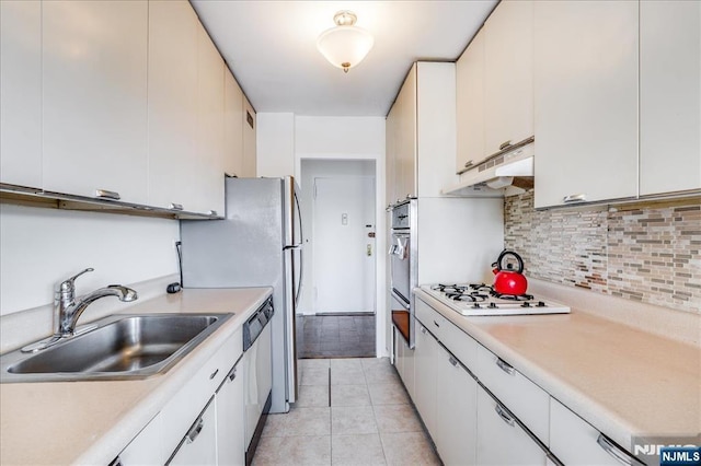 kitchen featuring a sink, stainless steel appliances, under cabinet range hood, and light countertops