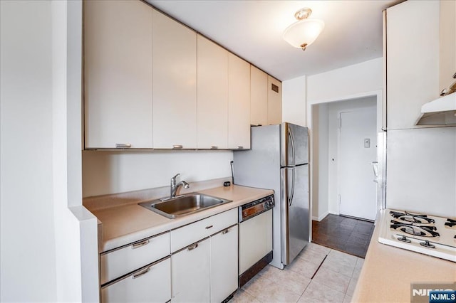 kitchen with a sink, under cabinet range hood, white appliances, light countertops, and light tile patterned floors