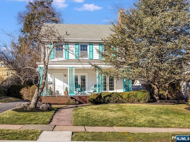 view of front of house with a front lawn, french doors, covered porch, and a shingled roof