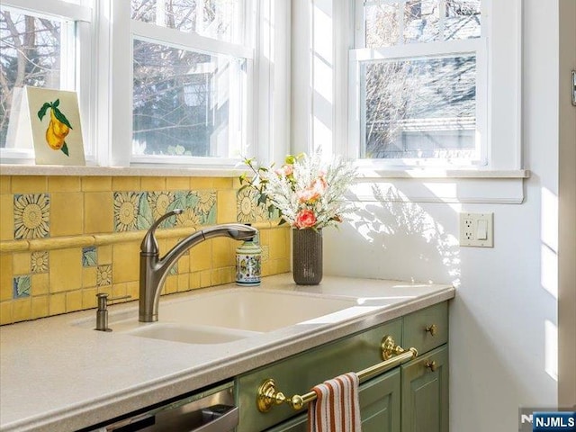 details with a sink, stainless steel dishwasher, green cabinets, and light countertops