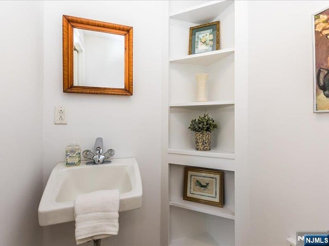 bathroom featuring built in shelves and a sink