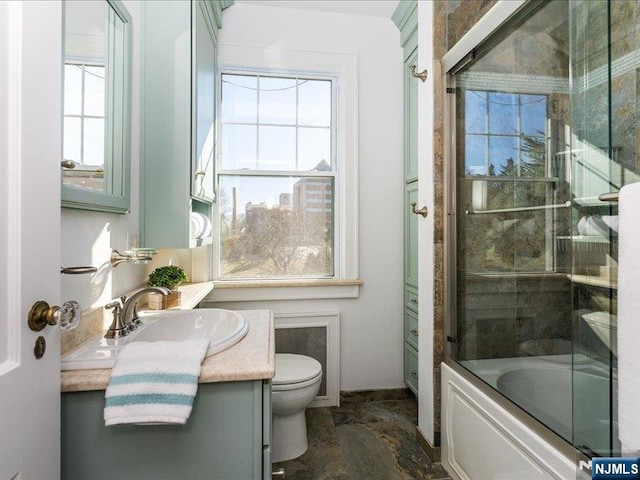 bathroom with combined bath / shower with glass door, toilet, and vanity