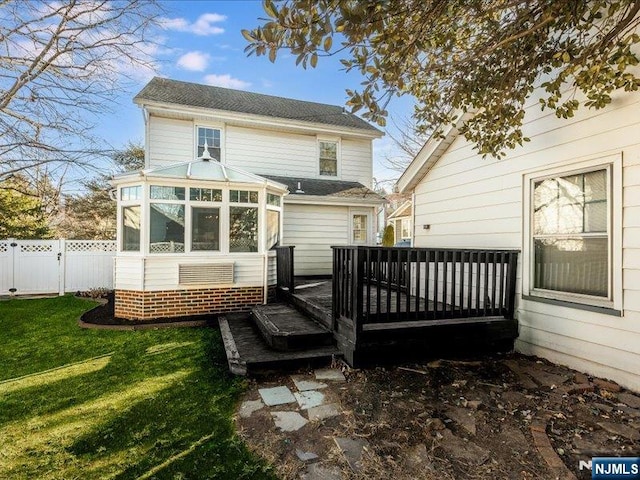 rear view of property featuring a yard, fence, a deck, and a sunroom