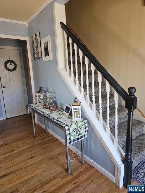 stairway with crown molding, baseboards, and wood finished floors