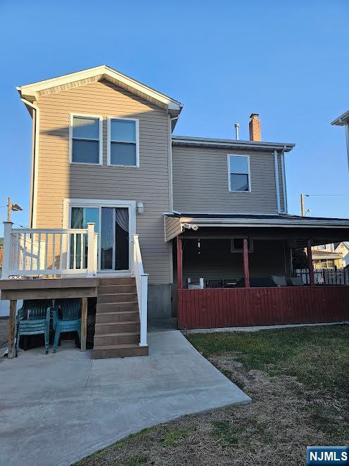 back of property with a deck and a chimney