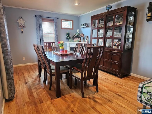 dining space with light wood-style flooring, baseboards, and ornamental molding