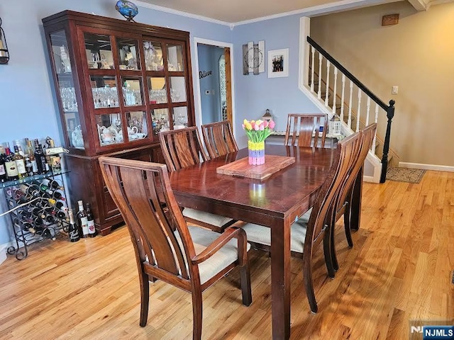 dining space featuring stairway, light wood-style flooring, crown molding, and baseboards