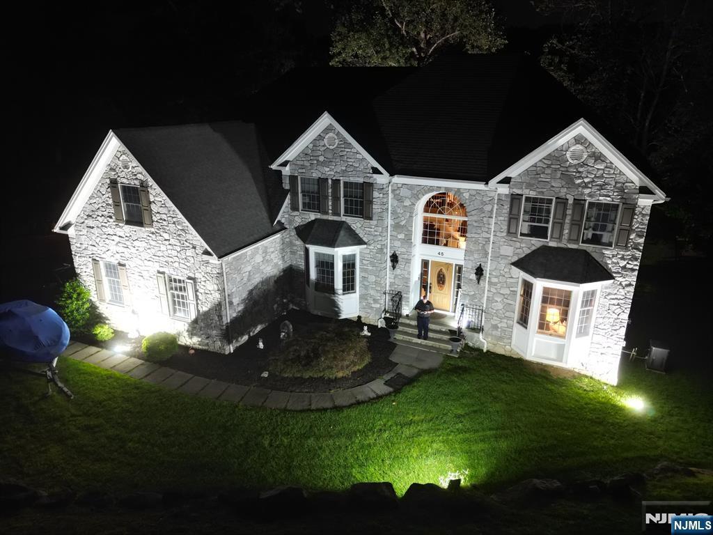 traditional home featuring stone siding and a front yard