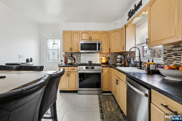 kitchen with a sink, plenty of natural light, light brown cabinets, and stainless steel appliances