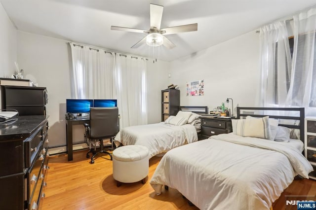 bedroom with baseboard heating, light wood-style flooring, and a ceiling fan