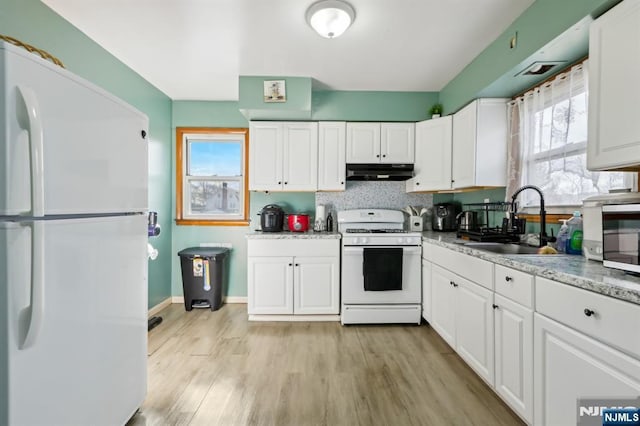 kitchen featuring under cabinet range hood, white appliances, white cabinets, and a sink