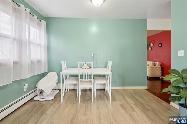 dining area with baseboards, baseboard heating, and wood finished floors