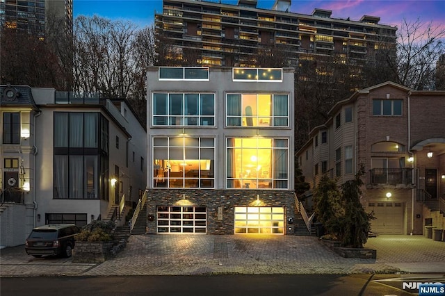 exterior space featuring driveway, an attached garage, and stairs