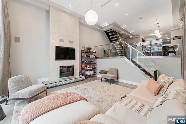 living area with a chandelier, a large fireplace, recessed lighting, and stairs