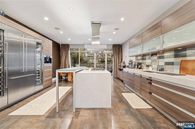 kitchen featuring tasteful backsplash, glass insert cabinets, light countertops, island exhaust hood, and modern cabinets