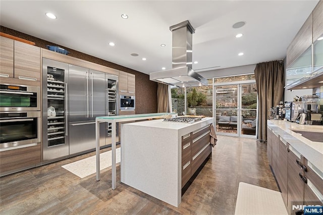 kitchen with island exhaust hood, light countertops, appliances with stainless steel finishes, modern cabinets, and a center island