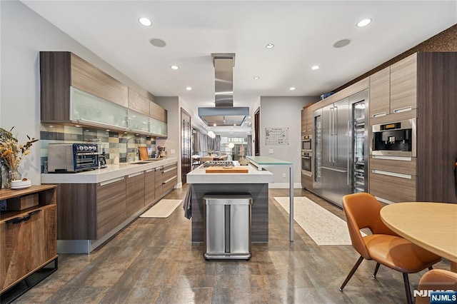 kitchen with modern cabinets, a kitchen island, island range hood, light countertops, and decorative backsplash