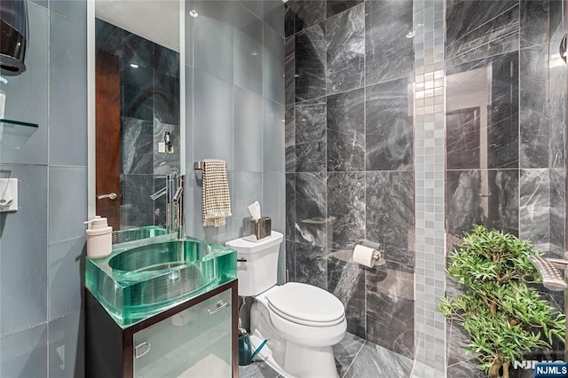 bathroom featuring toilet, tile walls, and vanity