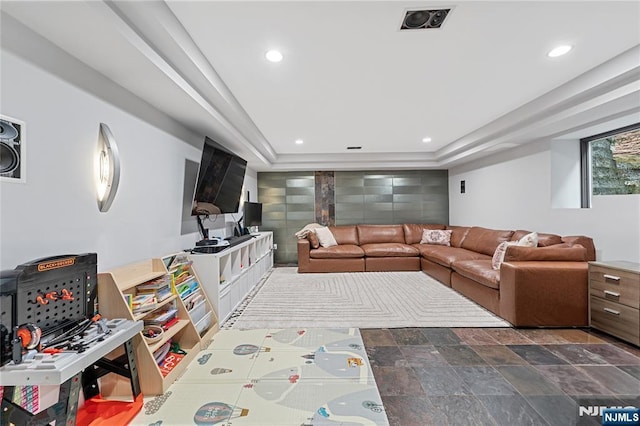 living room with an accent wall, stone finish floor, recessed lighting, and visible vents