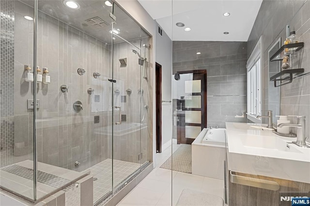 bathroom with tile patterned flooring, visible vents, a stall shower, a bath, and tile walls