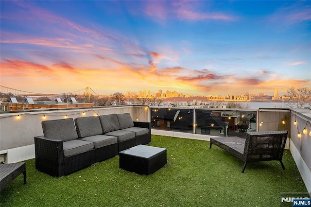 patio terrace at dusk featuring an outdoor living space, a yard, and a water view